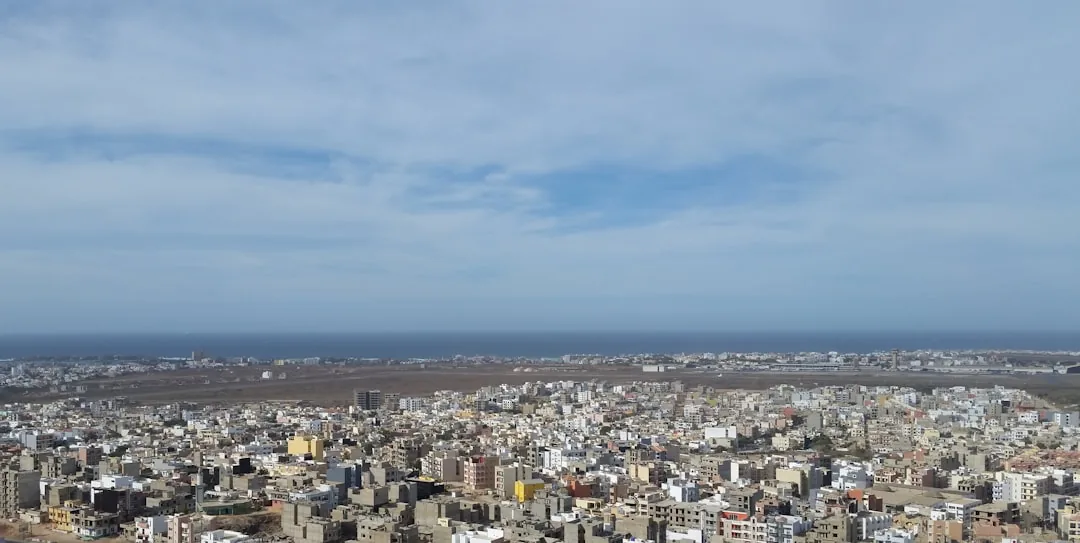 Vue panoramique aérienne de Dakar montrant l'urbanisation dense de la capitale sénégalaise avec bâtiments colorés et côte océanique