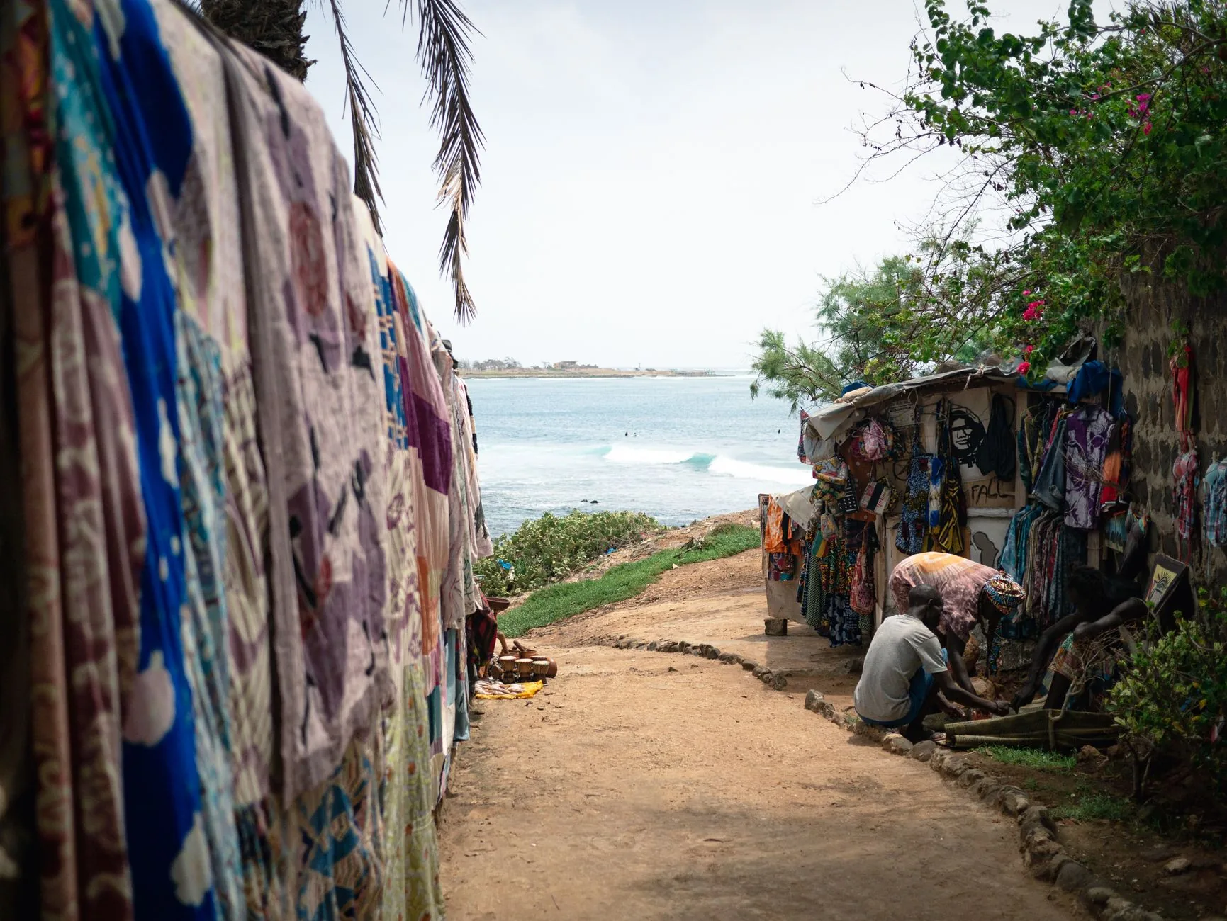 Petits commerces artisanaux et étals de vêtements colorés le long d'une plage côtière africaine
