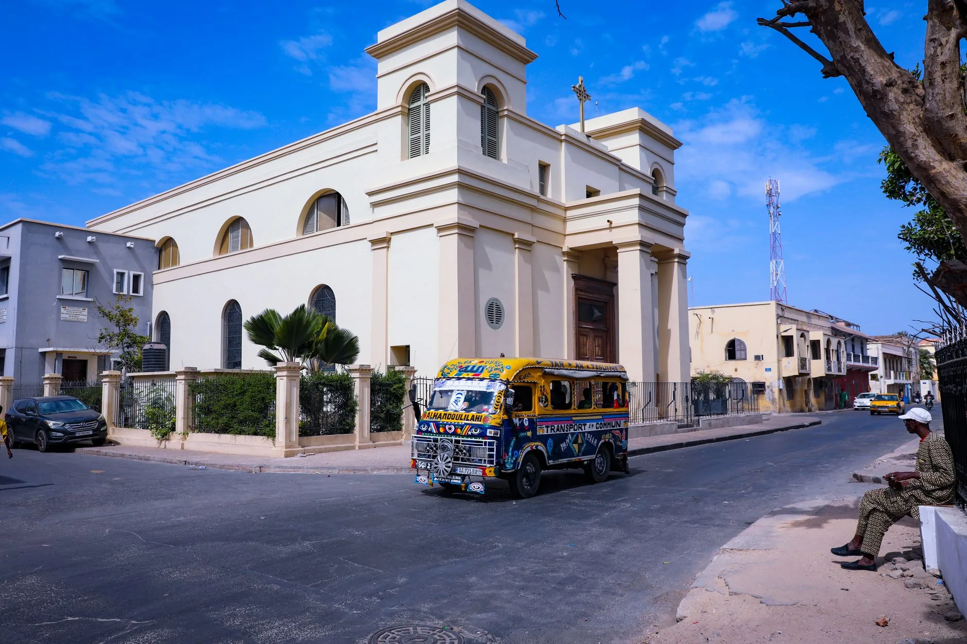 Église blanche avec minaret doré et transport coloré dans rue sénégalaise