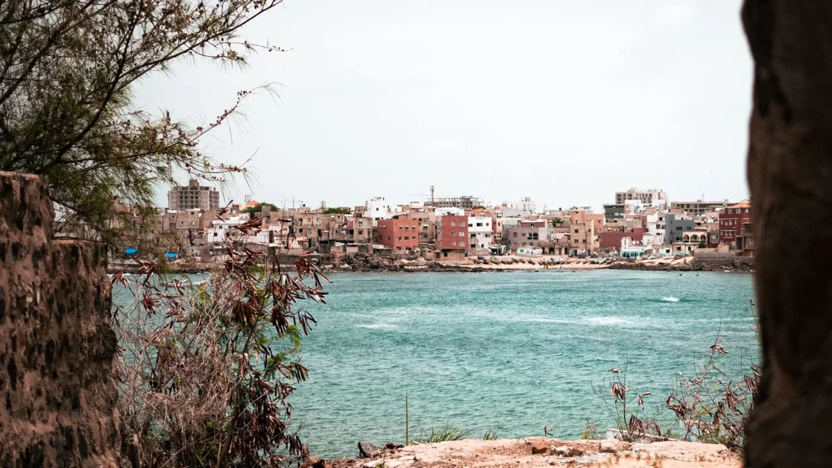 Vue côtière d'une ville sénégalaise avec maisons colorées surplombant la mer turquoise