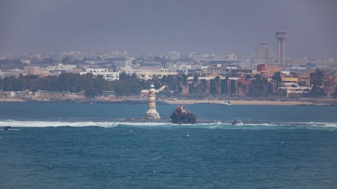 Phare de l'Île de Gorée avec la skyline de Dakar en arrière-plan