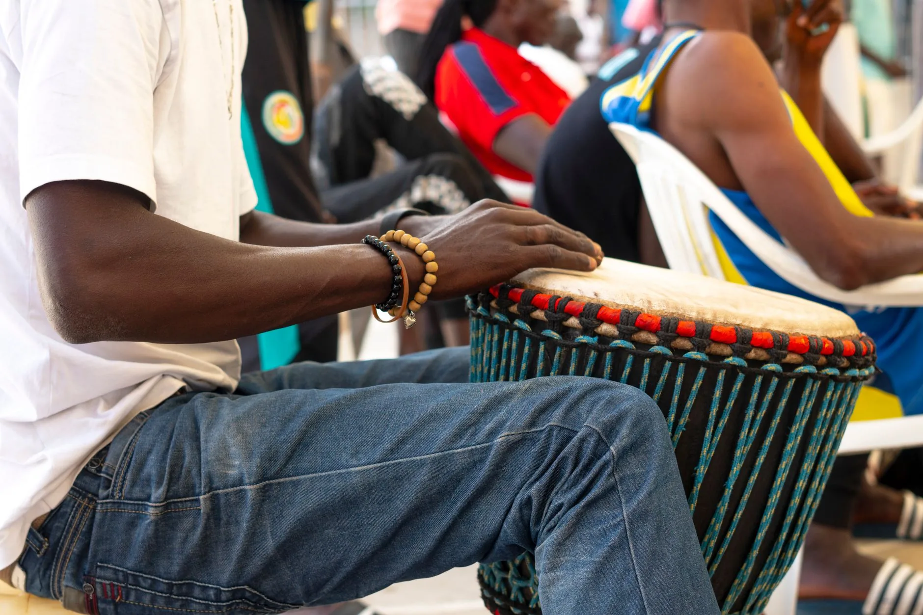Musicien jouant d'un djembé aux couleurs vives lors d'un rassemblement au Sénégal