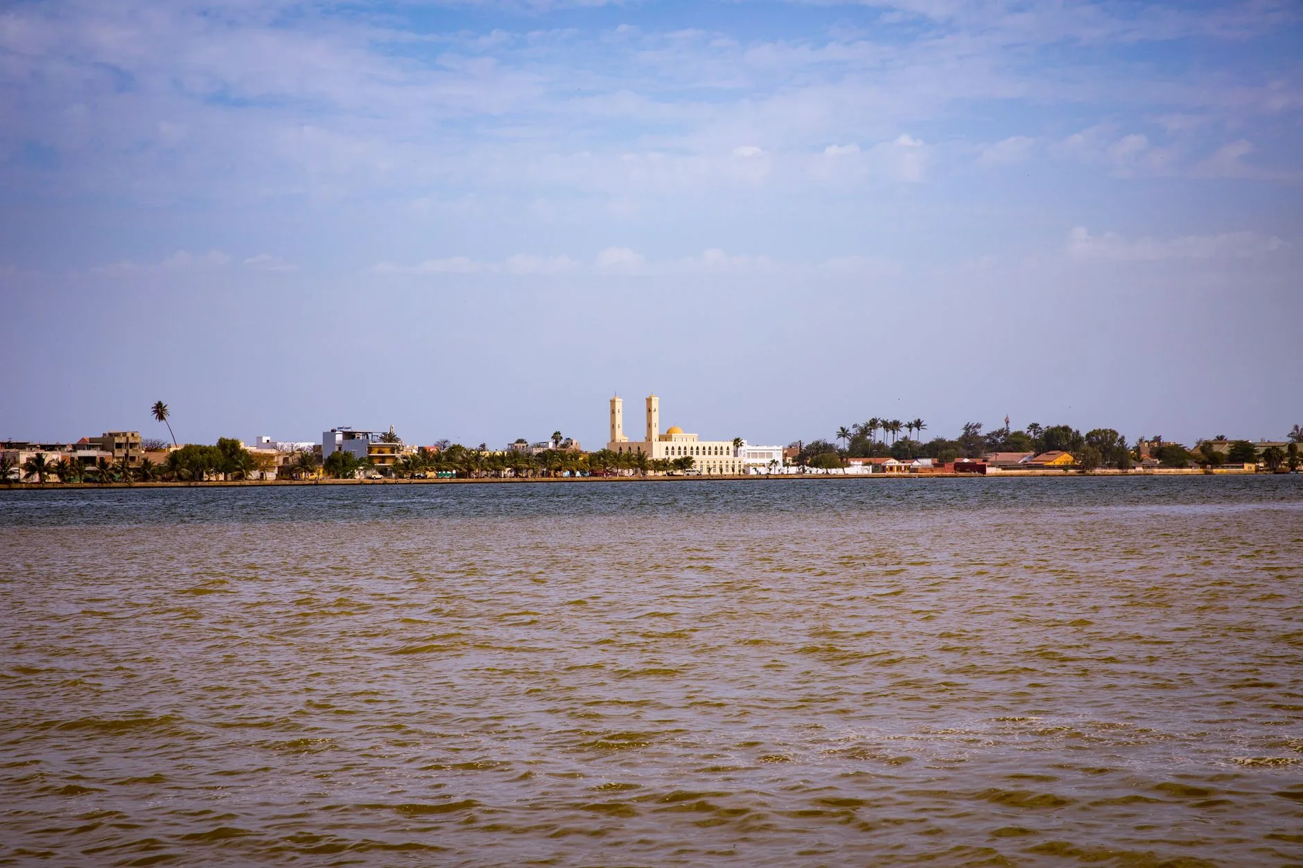 Vue depuis le fleuve sur une ville avec une mosquée à deux minarets et coupole dorée