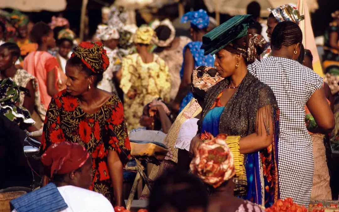 Femmes en tenues et coiffures colorées se déplaçant sur un marché animé